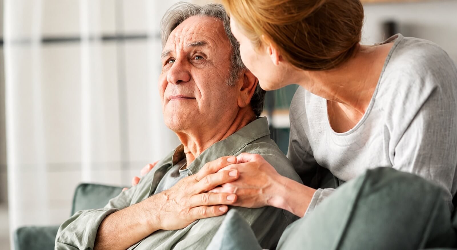 A caregiver resting a hand on a senior man’s shoulder