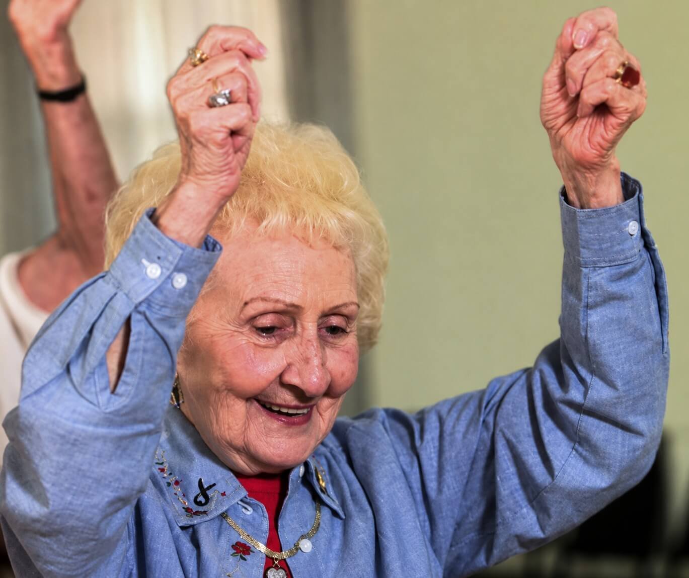 A senior woman dancing with her arms raised