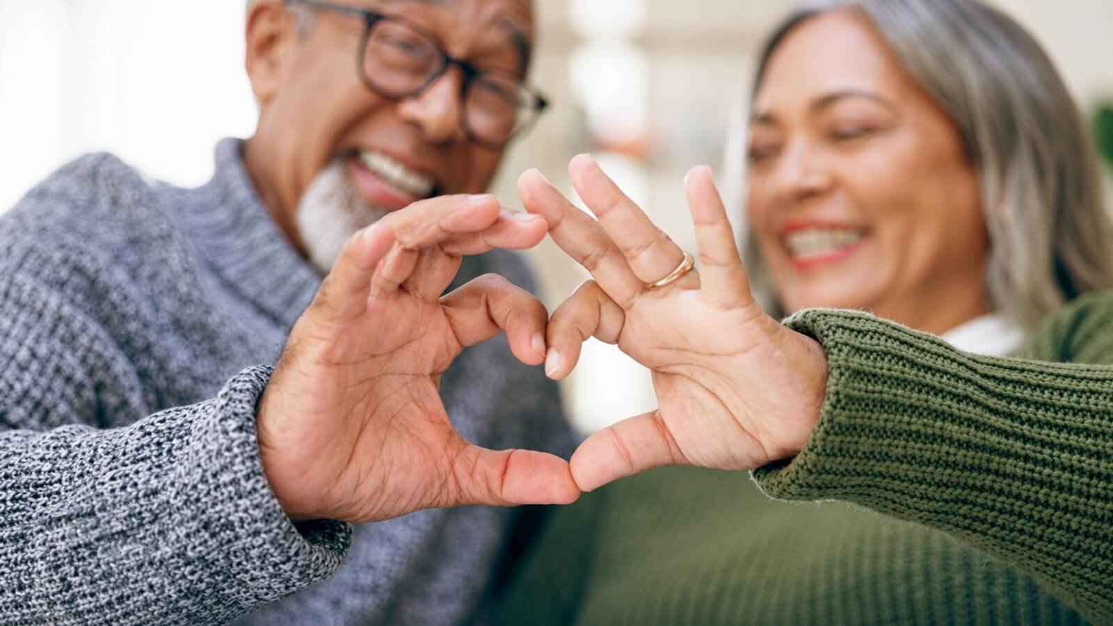 A senior couple making a heart with their hands